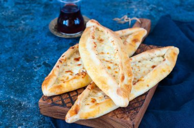 Turkish pide with cheese, popular street food in Turkey. Wooden background. Close up.