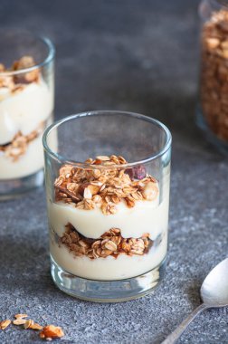 Granola with yogurt dessert in a glass. Gray background. Healthy eating or breakfast concept. Close up.