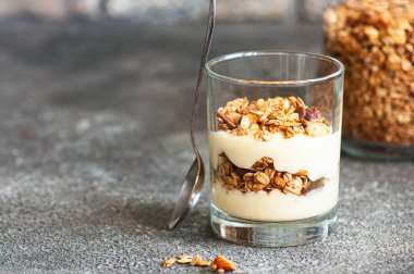 Granola with yogurt dessert in a glass. Gray background. Healthy eating or breakfast concept. Close up.