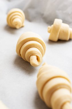 Semifinished or unbaked croissant on a baking sheet. Puff pastry baking. Close up.