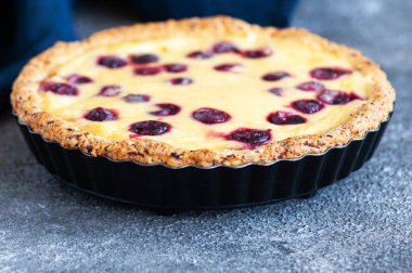 Gri arka planda kirazlı ev yapımı ricotta peynirli turta. Kapatın. Yürekli pişirme.