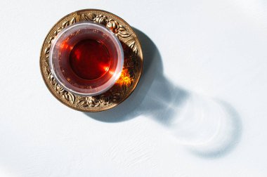 Bardakta kırmızı çay ve sert ışık. Sert gölgeler, üst manzara.