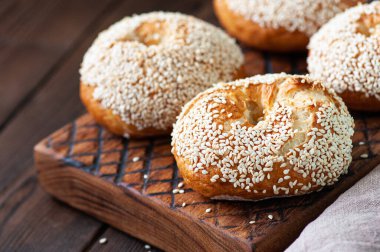 Tahta bir arka planda tahtadan yapılmış taze pişmiş susamlı simit. Kapat..