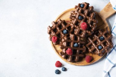 Tahta bir arka planda, tahta bir tabakta çikolatalı waffle ve böğürtlen. Üst görünüm ve kopyalama alanı.
