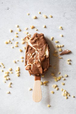 Çatlak vanilyalı bademli dondurma ve gri bir arka planda çikolata jöleli tahta çubuk. Üst görünüm.