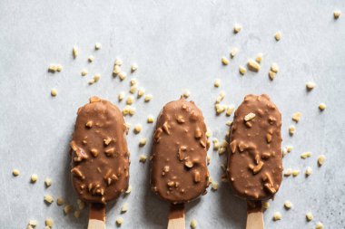 Tahta bir çubukta üç çikolatalı bademli dondurma. Üst görünüm.