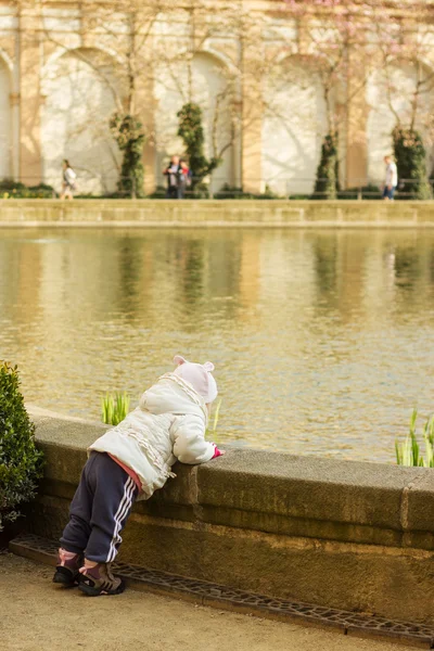 Babymeisje is wandelen in de buurt van een vijver — Stockfoto