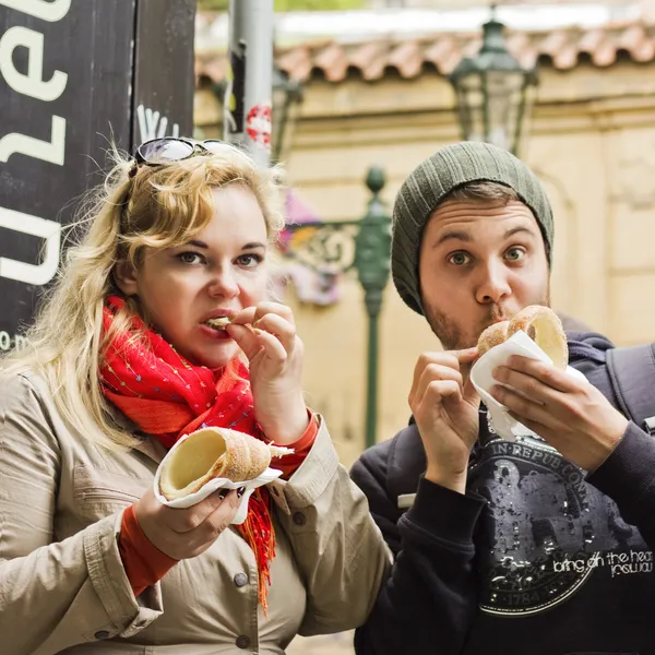 Young couple sitting eating pastry — Stock Photo, Image