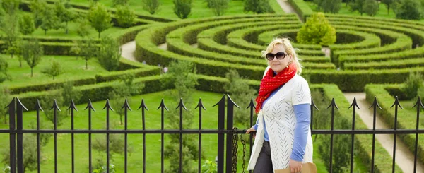 Smiling blond young woman against a garden labyrinth — Stock Photo, Image