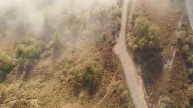 Alçak bulutlar üzerinde hava aracı uçuş manzarası ve güneş doğarken dağ yamaçlarını kaplayan sabah sisi. Dağlarda gün doğumu bulutlar.
