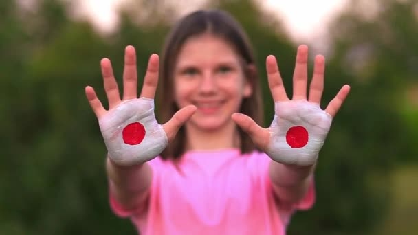 Gelukkig outdoor portret van kind meisje met de handen geschilderd in Japan vlag kleuren. Creatief. Selectieve focus — Stockvideo