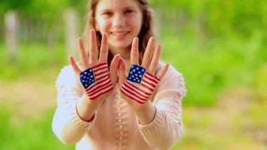 Amerikan bayrağı renginde boyalı ellerle el sallayan tatlı bir genç kız. ABD 4 Temmuz 'u kutluyor. Bağımsızlık Günü 