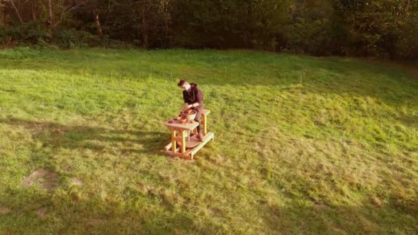 Aerial orbital snapshot of ceramic artist pottery concentrated on work with wheel pot clay outdoor on green meadow at amazing sunset. Creative workshop shaping or sculpting. Fine motor skills — Stockvideo