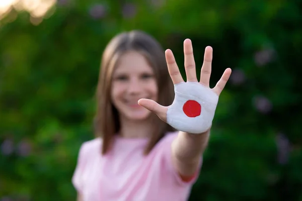 Παιδί κορίτσι δείχνουν στάση χειρονομία με τα χέρια βαμμένα σε χρώματα σημαία της Ιαπωνίας. Ανοίξτε ξανά το σχολείο, Υγεία. Μάθετε ιαπωνικά. — Φωτογραφία Αρχείου