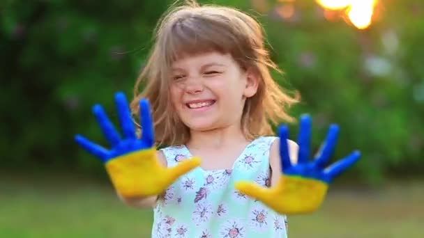 귀여운 소녀가 날으는 머리로 머리를 흔들면서 느린 동작을 하는 것이다. 우크라이나 국기 색으로 손을 그린 어린이 — 비디오
