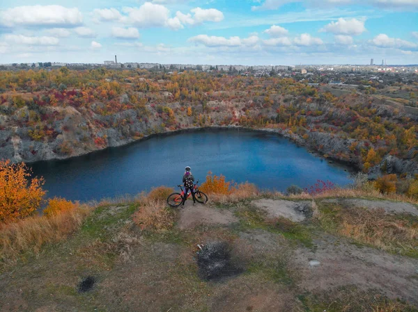 Joven mujer ciclismo en bicicleta al aire libre vista aérea desde arriba. Vista aérea de la chica del deporte feliz relajándose cerca de hermosas montañas lago, deporte y fitness concepto — Foto de Stock