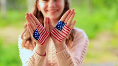 Amerikan bayrağı renginde boyalı ellerle el sallayan tatlı bir genç kız. ABD 4 Temmuz 'u kutluyor. Bağımsızlık Günü, Anma Günü, Bayrak Günü 14 Haziran