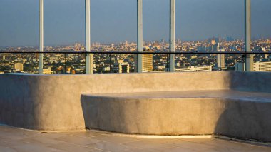 Apartman terası. Oturmak ve dinlenmek için çimentodan yapılmış koltuklar var. Şehrin ve gökyüzünün manzarası için gün batımını izleyin.