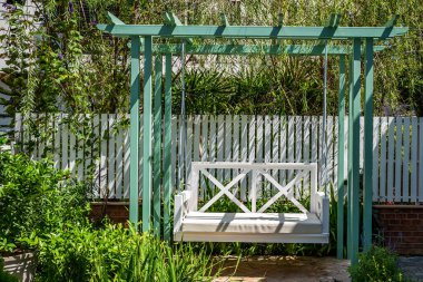 Bahçede boş zaman için yeşil bir ahşap salıncak.