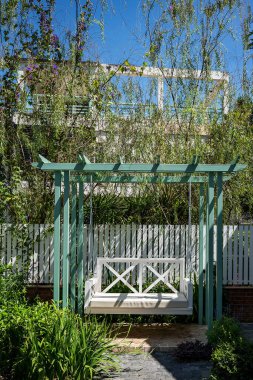 Bahçede boş zaman için yeşil bir ahşap salıncak.