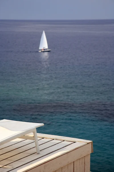 Сонячне ліжко і вітрильний човен — стокове фото