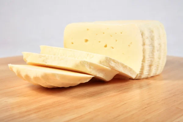 Block of cheese on a wooden plate with decoration — Stock Photo, Image