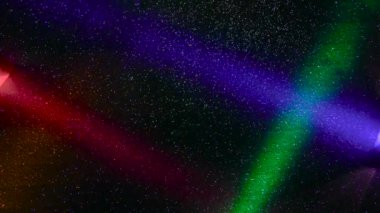 Multi-colored beams of light blink on a dark background.