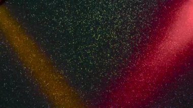 Multi-colored beams of light blink on a dark background.