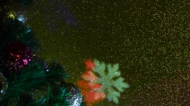 Noel ağacı şenlikli toplarla süslenmiş. Renk değiştiren yanıp sönen bir arkaplanda farklı renklerde ışık huzmeleri. Noel ağaçlarının ve kar tanelerinin uçan renkli siluetleri.