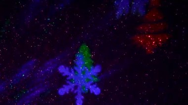 A carousel of light beams of different colors is set against a constantly flashing background that changes colors. Flying colored silhouettes of Christmas trees and snowflakes.