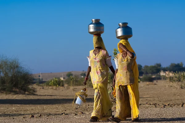 Women lugging water pot on head — Stock Photo, Image