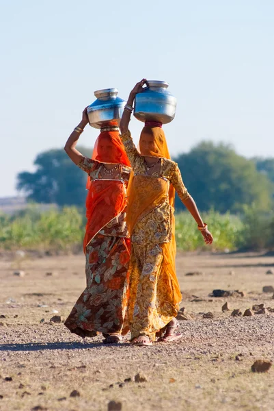 Women lugging a water pot on their head — Stock Photo, Image