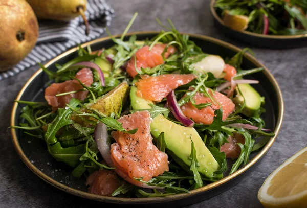Tabakta sağlıklı avokado, somon ve roka salatası.
