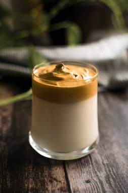 Koyu ahşap masada bir bardak dalgona kahve.