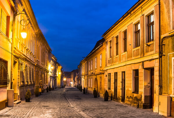 Brasov, Transylvania. Night scene of medieval paved street in downtown of the city. Saxon landmark in Romania.