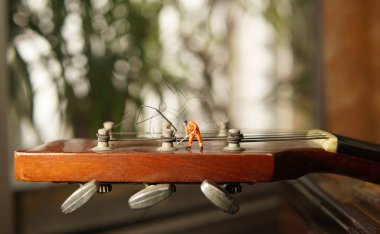 Eski gitar tellerini tamir eden teknisyen figürü. 