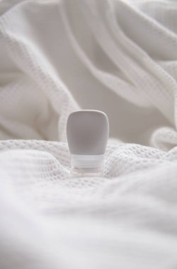 Beyaz kumaş arka planında losyon tübü modeli izole edildi.