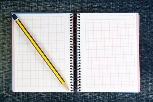 An open notebook on jeans and a pencil. — Stock Photo, Image