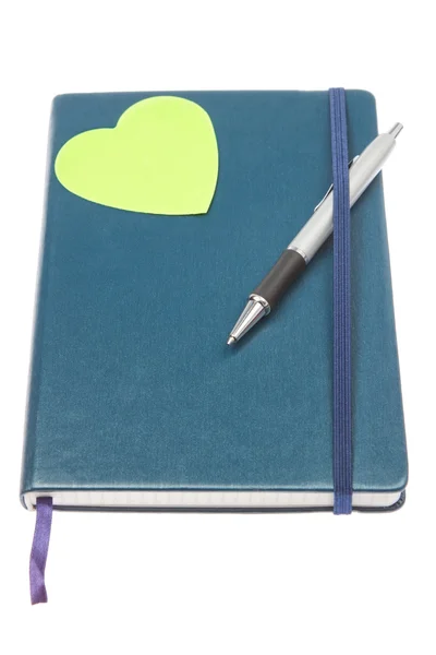 Cuaderno cerrado con una pluma y un corazón verde. — Foto de Stock