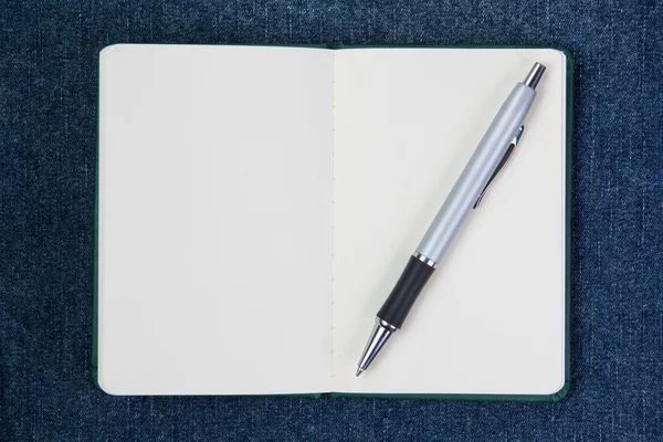 Kugelschreiber auf einem sauberen Notebook. auf blauem Hintergrund. — Stockfoto