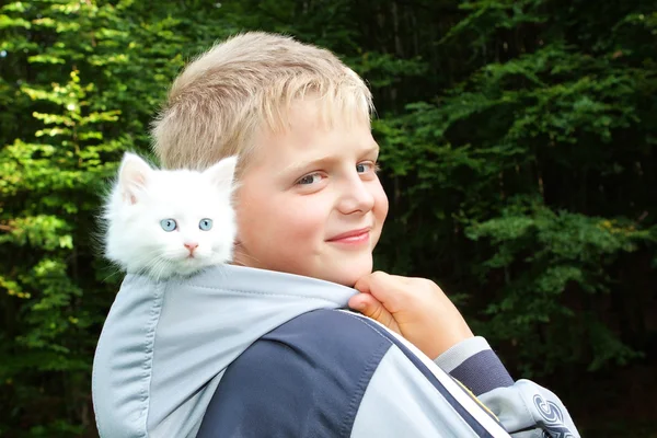 Een jongen en een witte kitten in de kap. in de natuur. — Stockfoto
