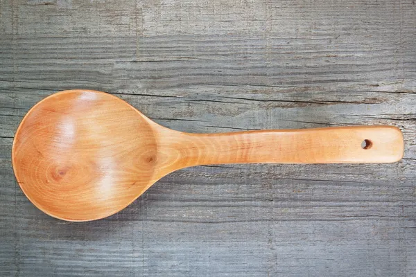 Old wooden spoon on textured board. — Stock Photo, Image