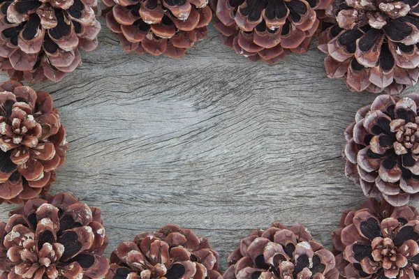 Marco de Navidad con conos, protuberancias en una textura de madera. —  Fotos de Stock