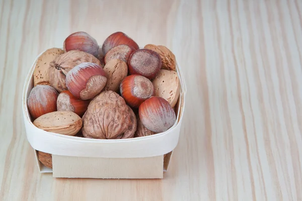 Basket with wood, walnuts and almonds. On a wooden texture. — Stock Photo, Image