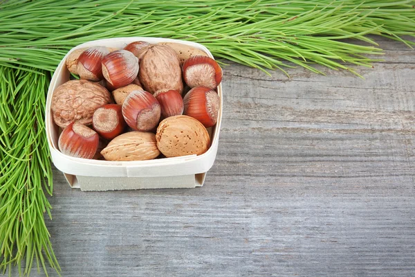 Christmas basket with wood, walnuts and almonds. On a wooden tex — Stock Photo, Image