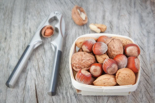 Nutcracker and a hazelnut with a basket of various nuts. — Stock Photo, Image