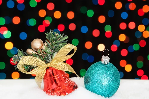 Campana de Navidad y la bola en la nieve. en el fondo bokeh. —  Fotos de Stock