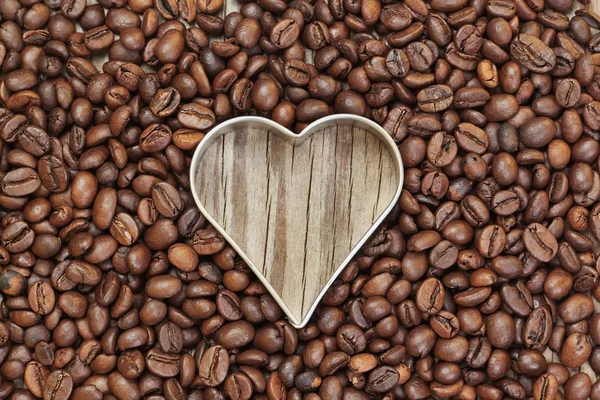 Heart shape in coffee beans on a wooden texture. — Stock Photo, Image