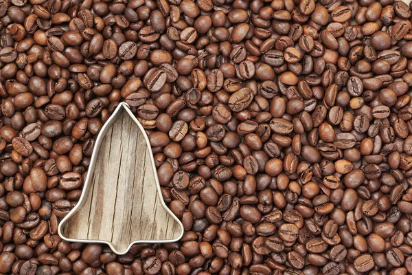 Shape of a Christmas bell in coffee beans on a wooden texture. — Stock Photo, Image