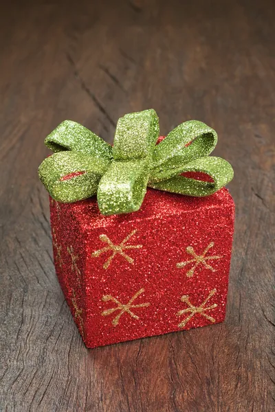 Contenitore di regalo di Natale con un arco su una struttura in legno. — Foto Stock